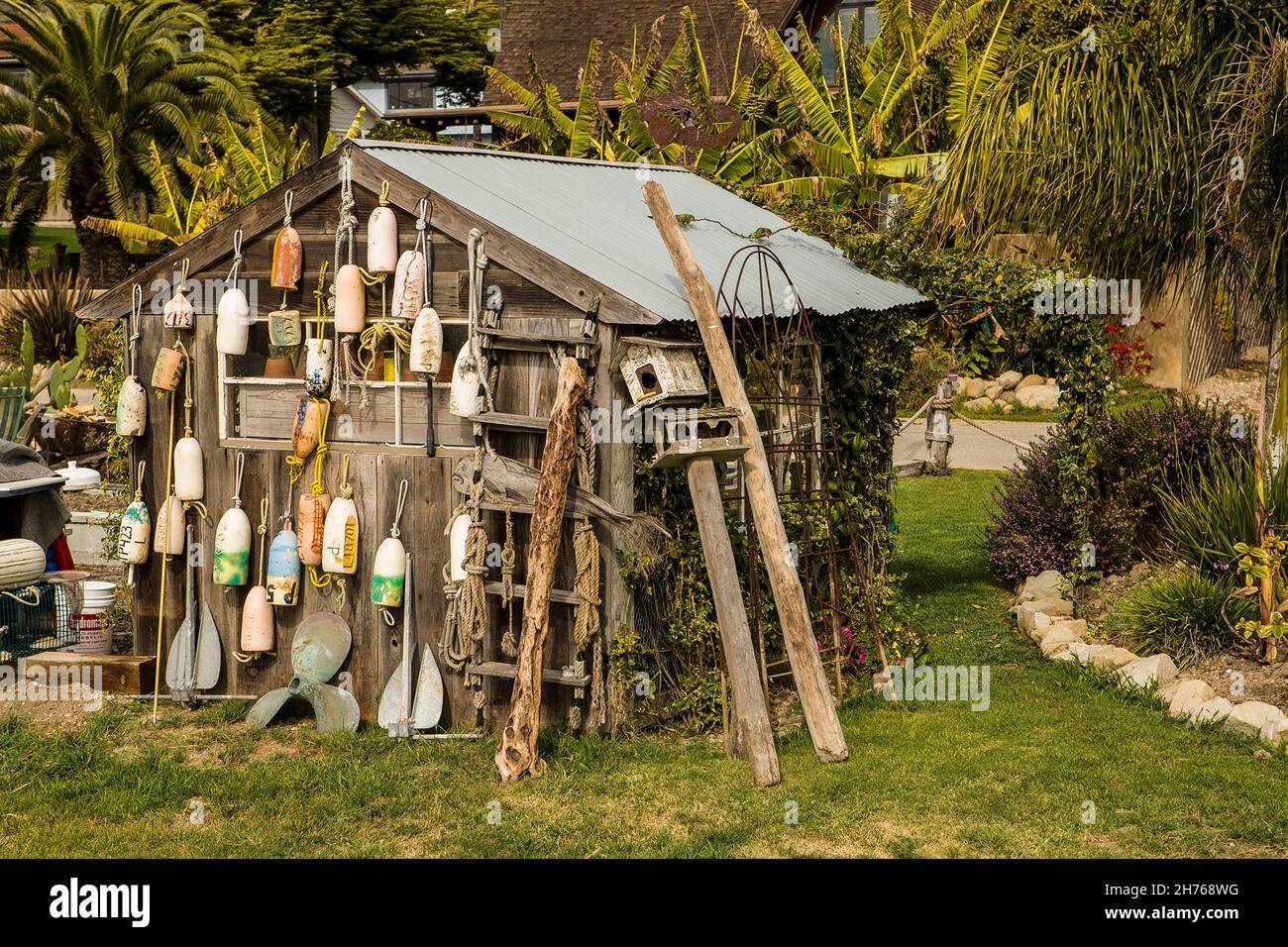 Many old buoys are hanging from the side of a wooden shed. Stock Photo