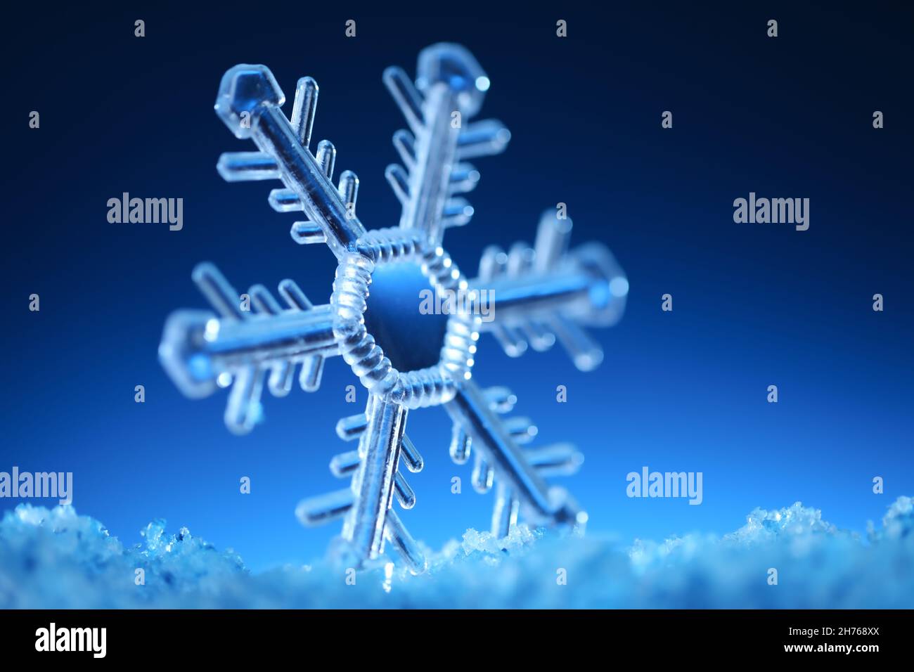 Clear snowflake crystal on sparkling snow. Cold or winter time concept. Stock Photo