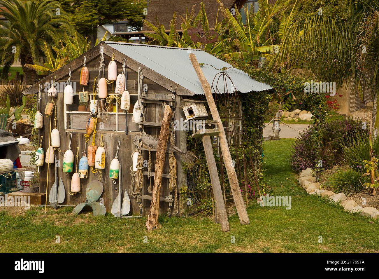 Many old buoys are hanging from the side of a wooden shed. Stock Photo