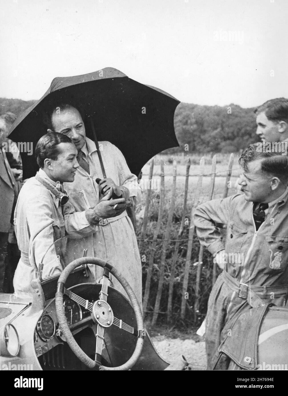 Prince B Bira from Siam (now Thailand) and Raymond Mays (both driving ERA's) with one of Bira's White Mouse Stable mechanics on the right. This is in the Donington Park paddock, on the day of the Nuffield Trophy, 10th June 1939 photograph Taken by T W Green. Stock Photo