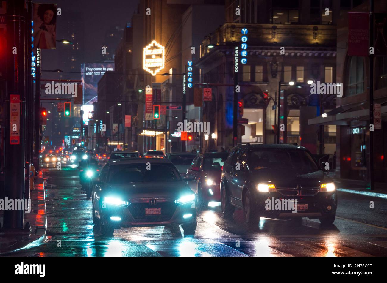 Toronto, Canada - 10 30 2021: Night rain pouring down on cars standing on traffic lights in Yonge street in downtown Toronto with bright colorful str Stock Photo