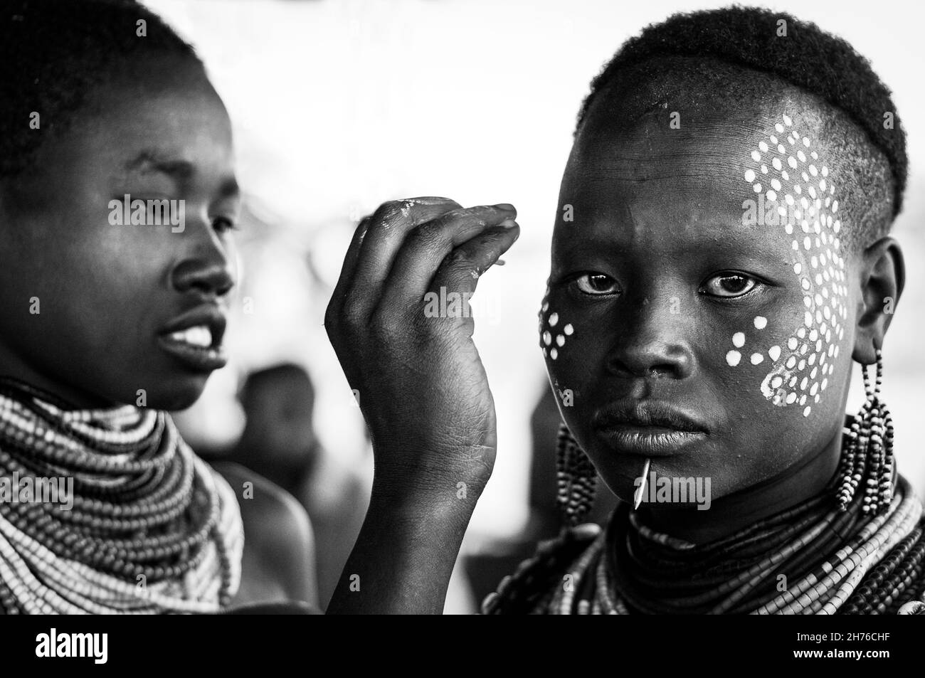 Karo woman painting white dots on another woman's face for decoration Stock Photo