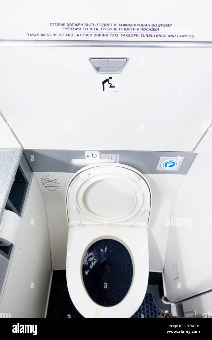 Narrow toilet cabin and seat in the bathroom of the Boeing 737-800 air carrier. Public convenience and restrooms on board of an airplane. Stock Photo