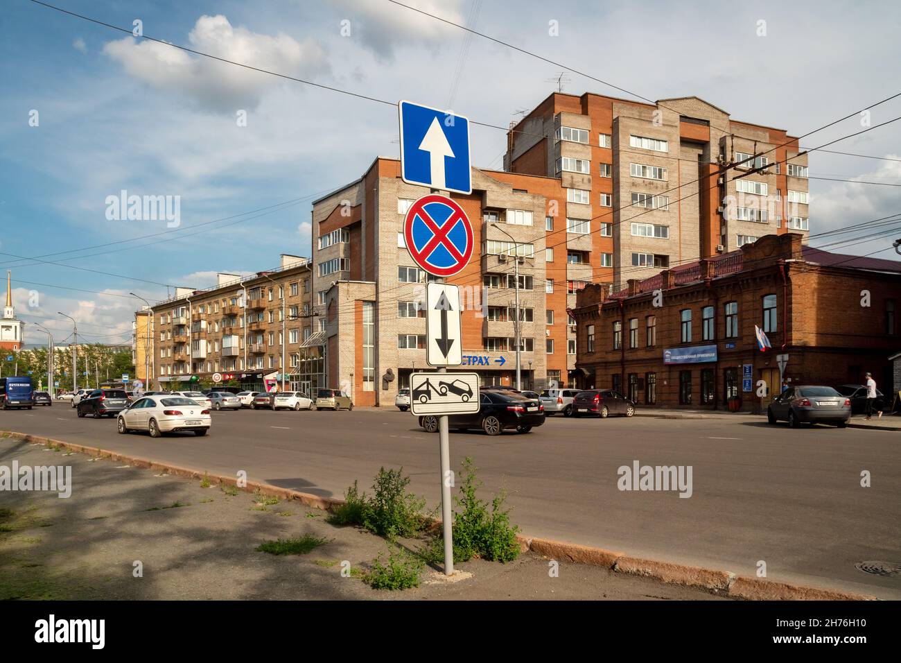 Road sign Stopping is prohibited stands on the Abalakov Brothers Street against the background of passing vehicles and city buildings in summer day Stock Photo