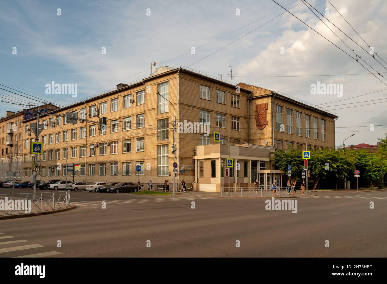 People walk to the pedestrian crossing past the Soviet-era Administrative Building at the corner of Karl Marx and Dekabristov streets in summer. Stock Photo