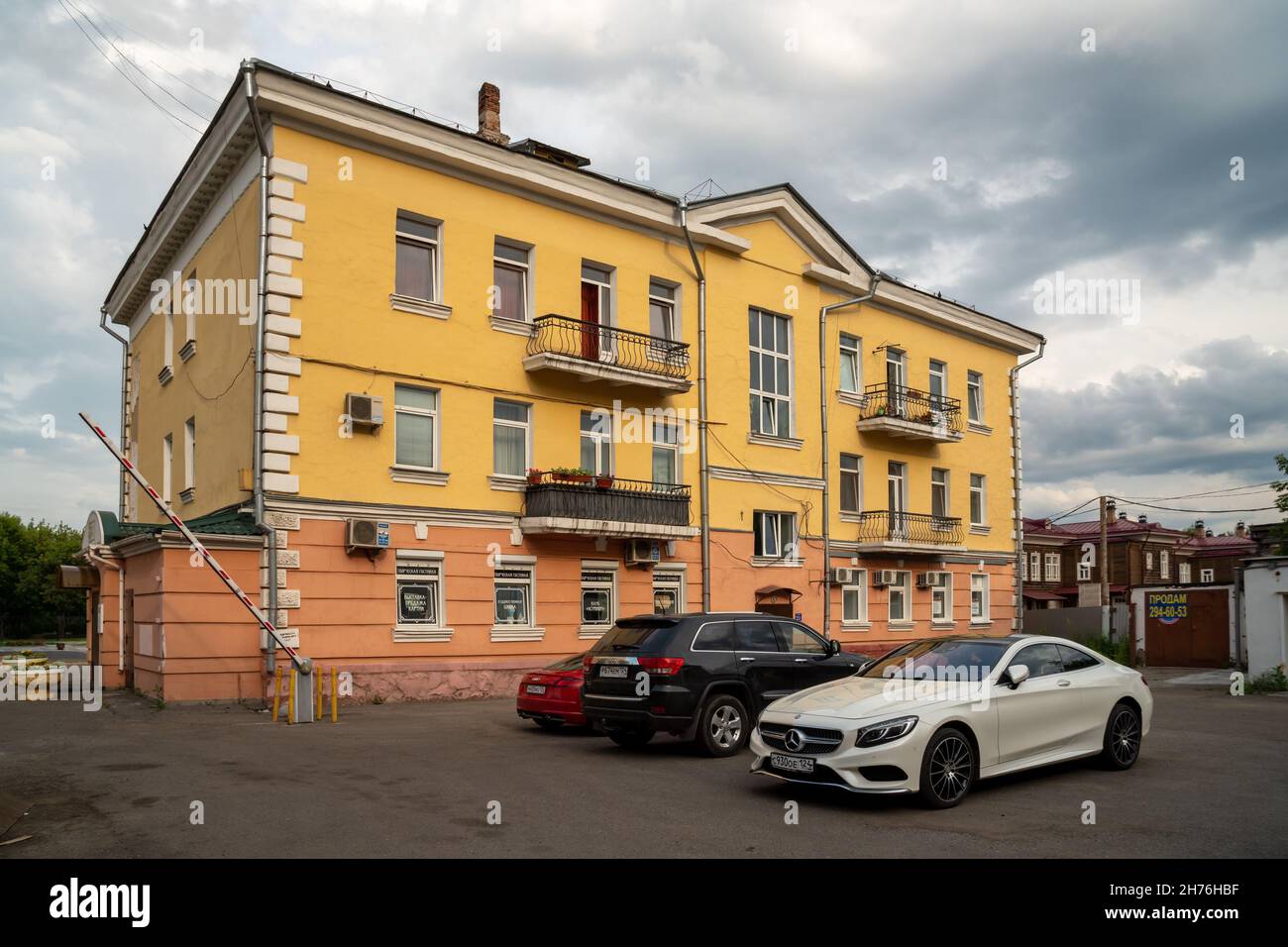 Cars are parked in the courtyard of a Stalin-era apartment building on a cloudy summer day. Stock Photo