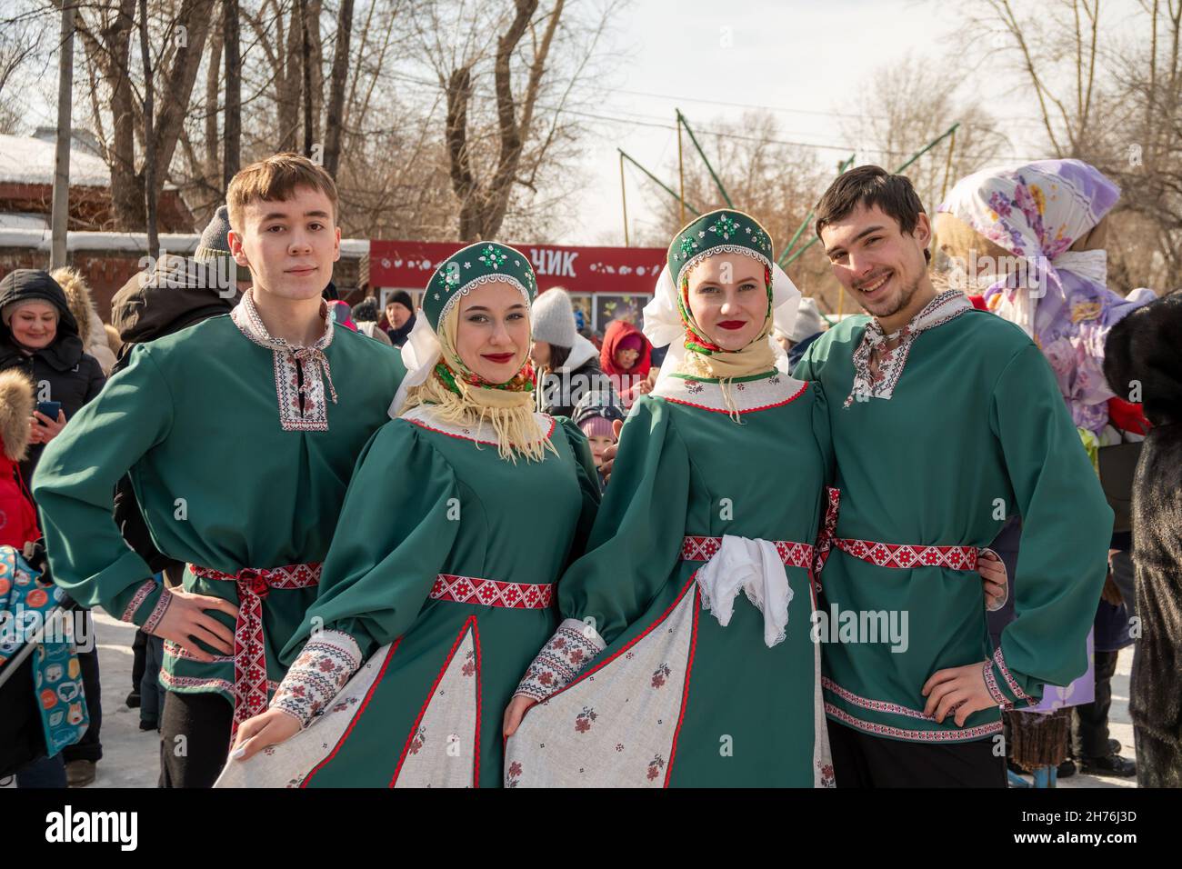 Young people in Russian ethnic costumes pose against the backdrop of a