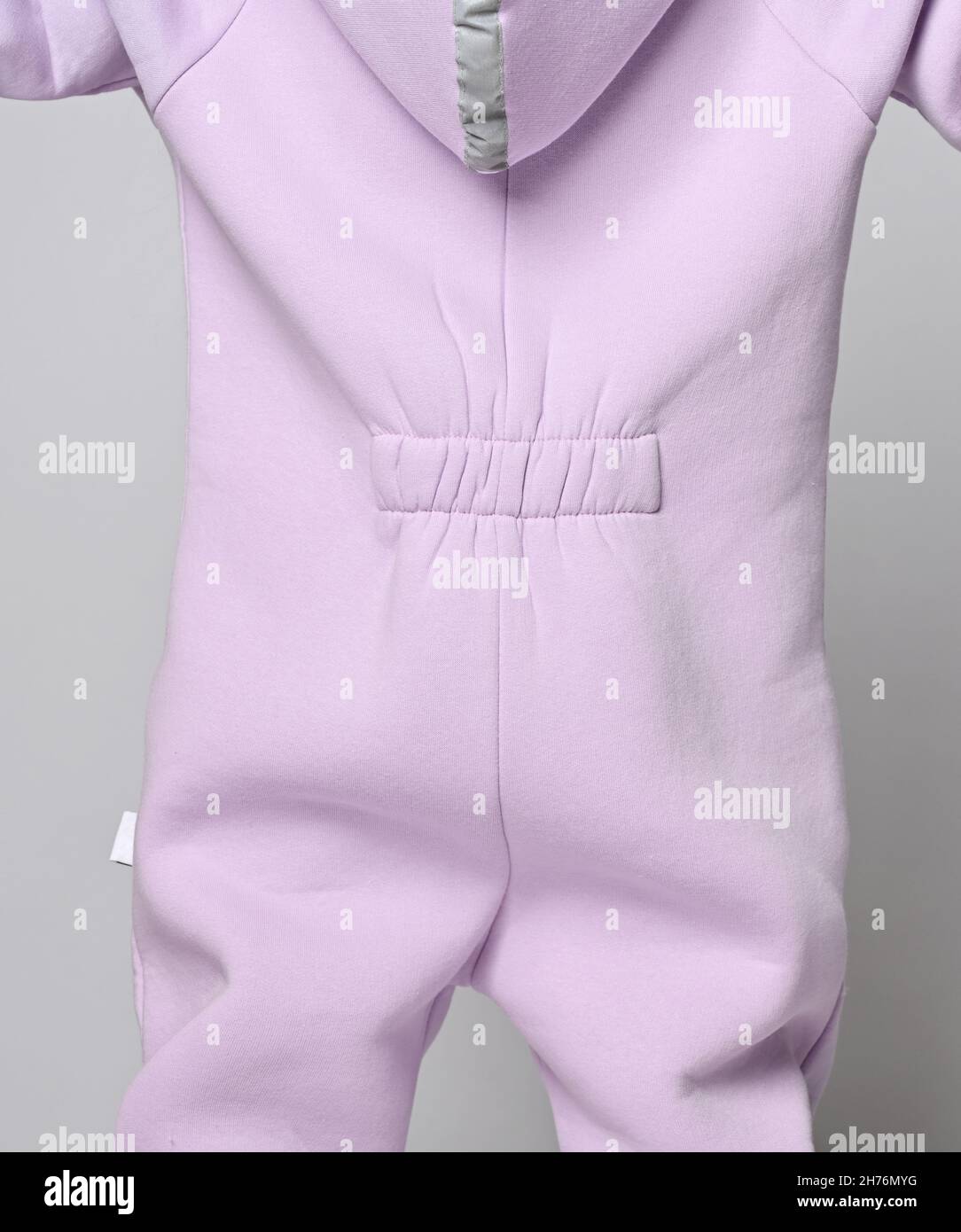 Closeup of kid girl in pink jumpsuit with elastic band on lower back and hood with retroreflective strip. Back view. Stock Photo