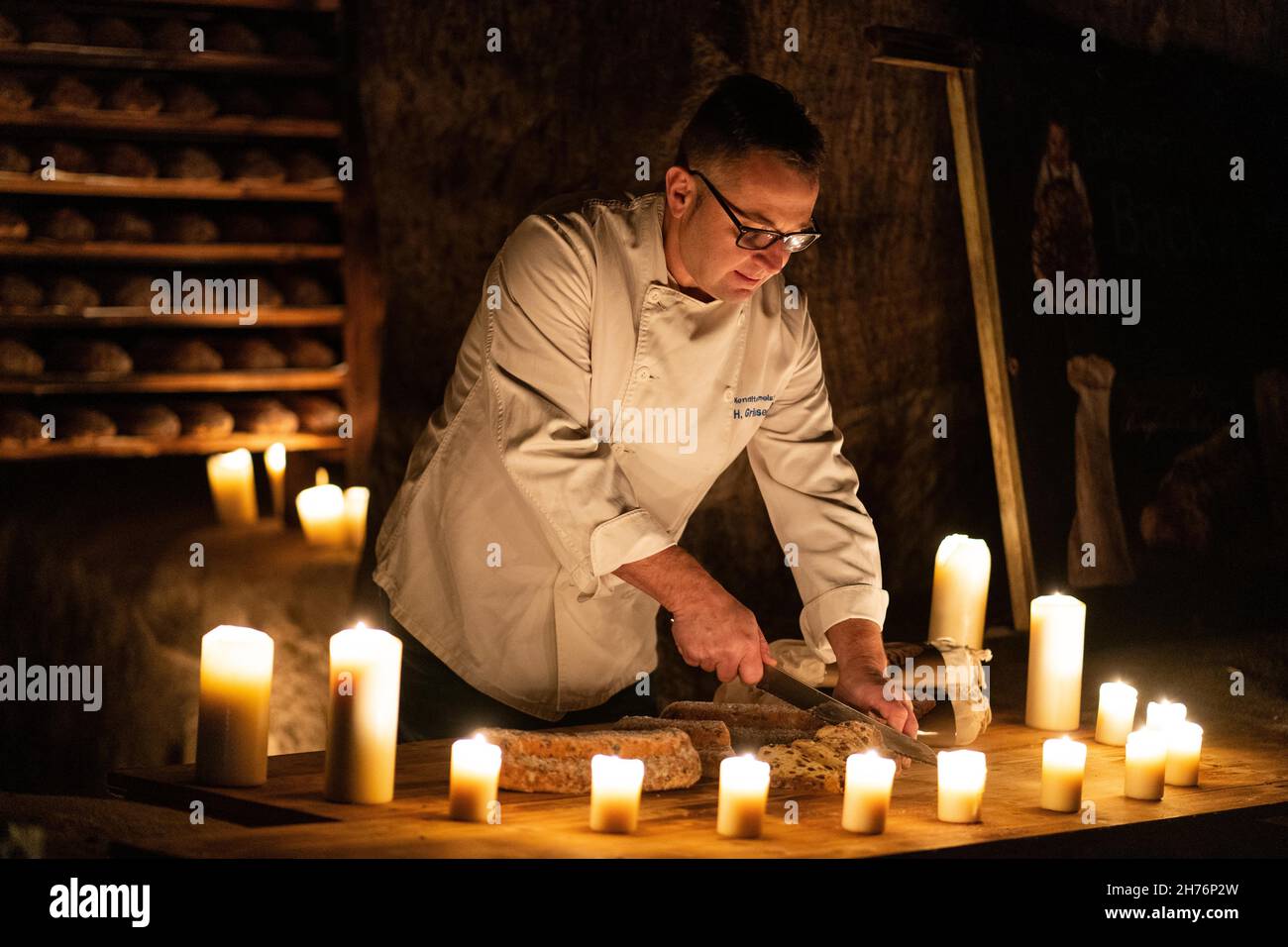 Kulmbach, Germany. 19th Nov, 2021. Master baker Holger Griesenbrock cuts one of his stollen stored in a rock cellar. In the historic rock cellars under Plassenburg Castle in Kulmbach, very special Christmas cookies are currently being stored: master baker Holger Griesenbrock is maturing his stollen here. The stollen remain deep under the imposing castle complex for three to four weeks - to become particularly moist. Credit: Nicolas Armer/dpa/Alamy Live News Stock Photo