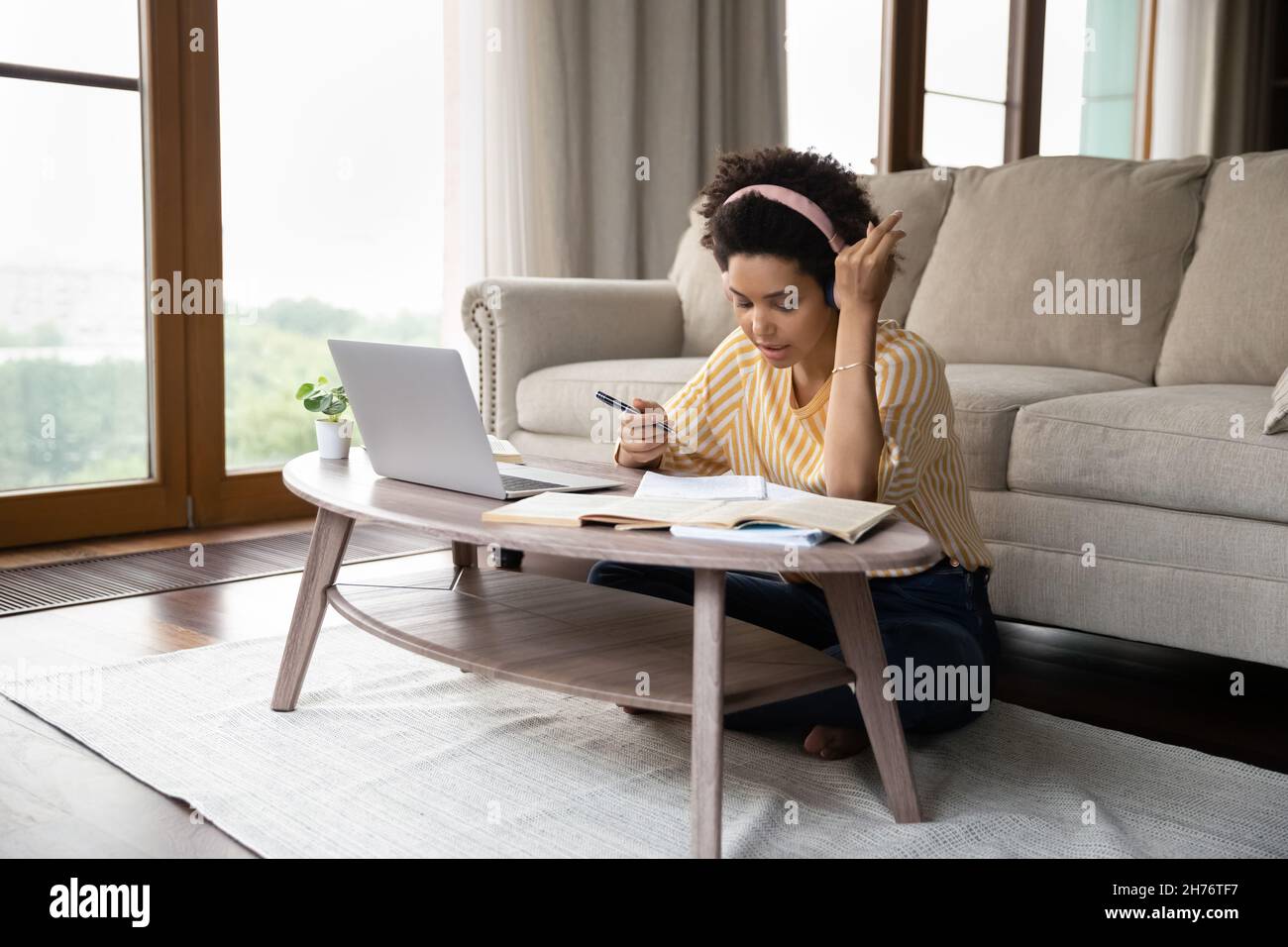 Focused Black female student in headphones engaged in studying Stock ...