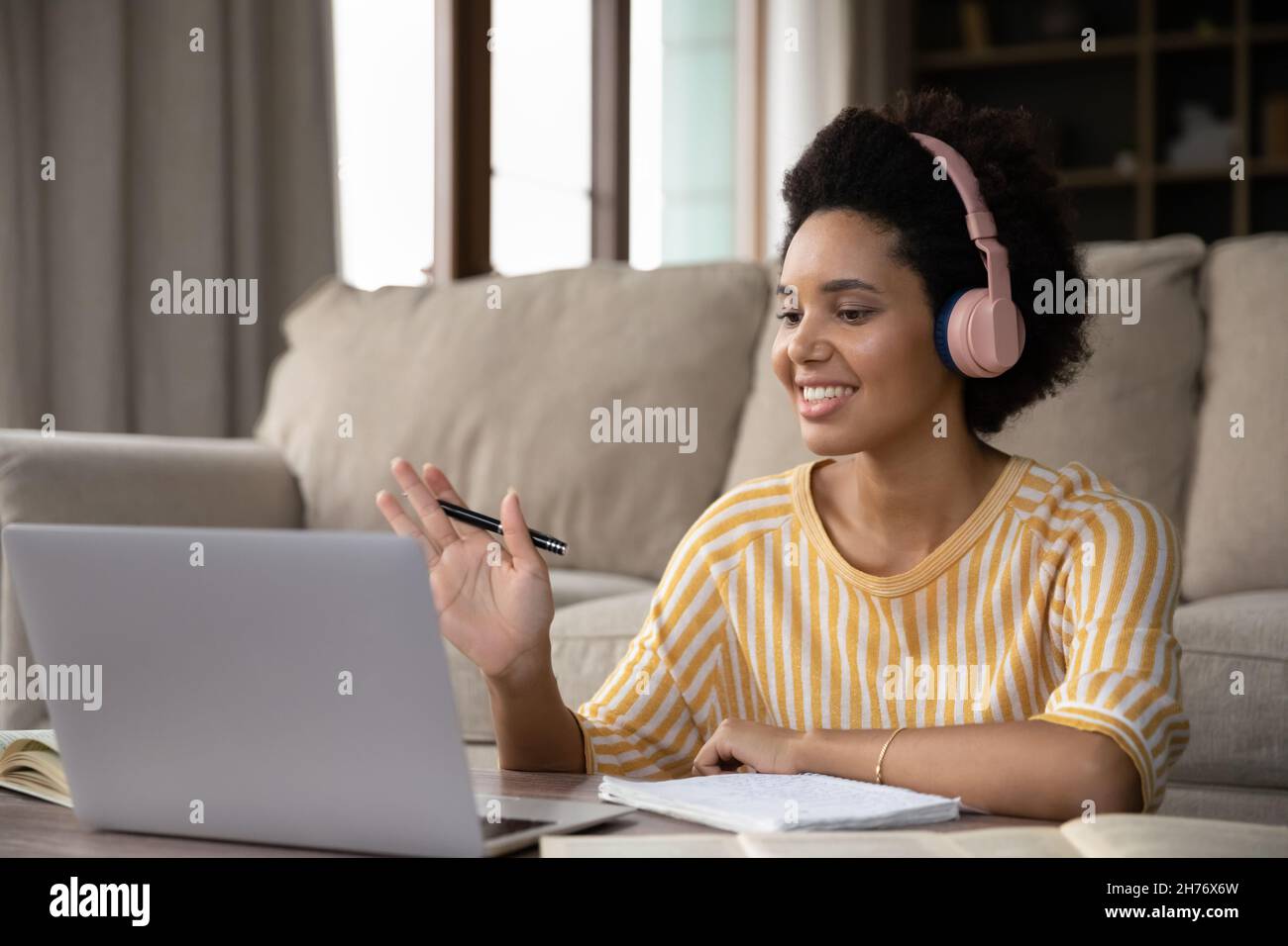 Happy African American student girl in wireless headphones studying ...