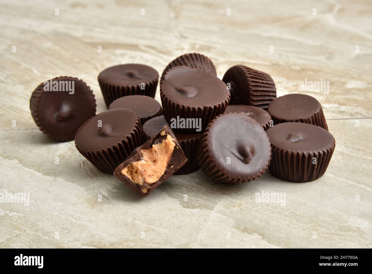 A mound of chocolate peanut butter cups on a countertop with a missing bite Stock Photo