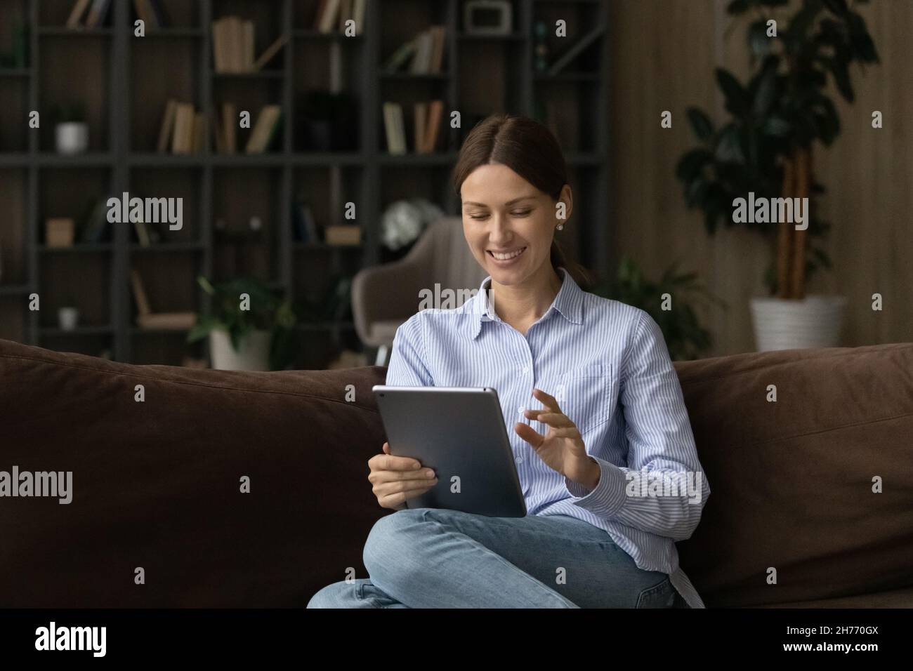 Beautiful young woman sit on couch using digital tablet Stock Photo - Alamy