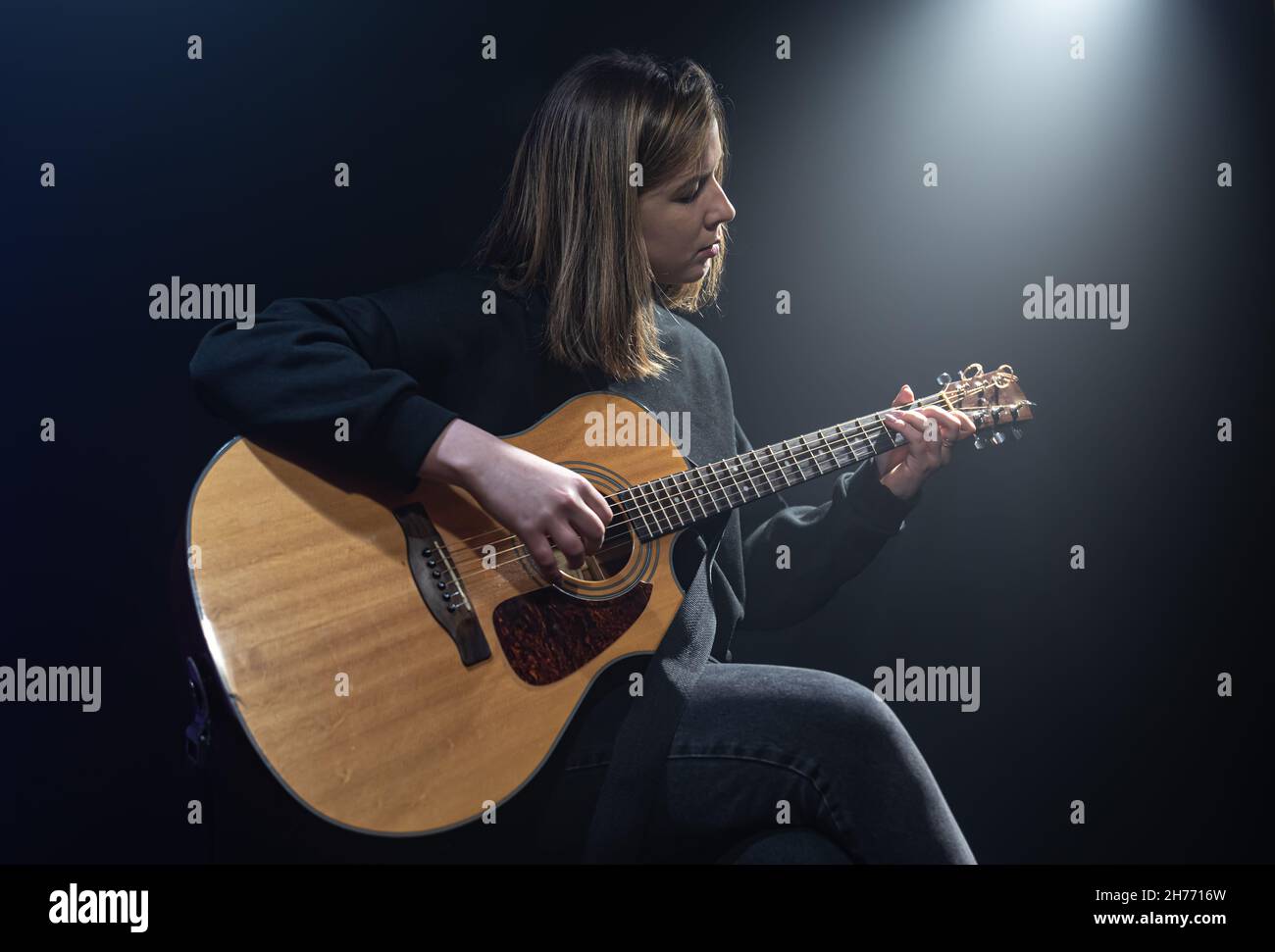 Young woman playing acoustic guitar in a dark room with haze Stock ...