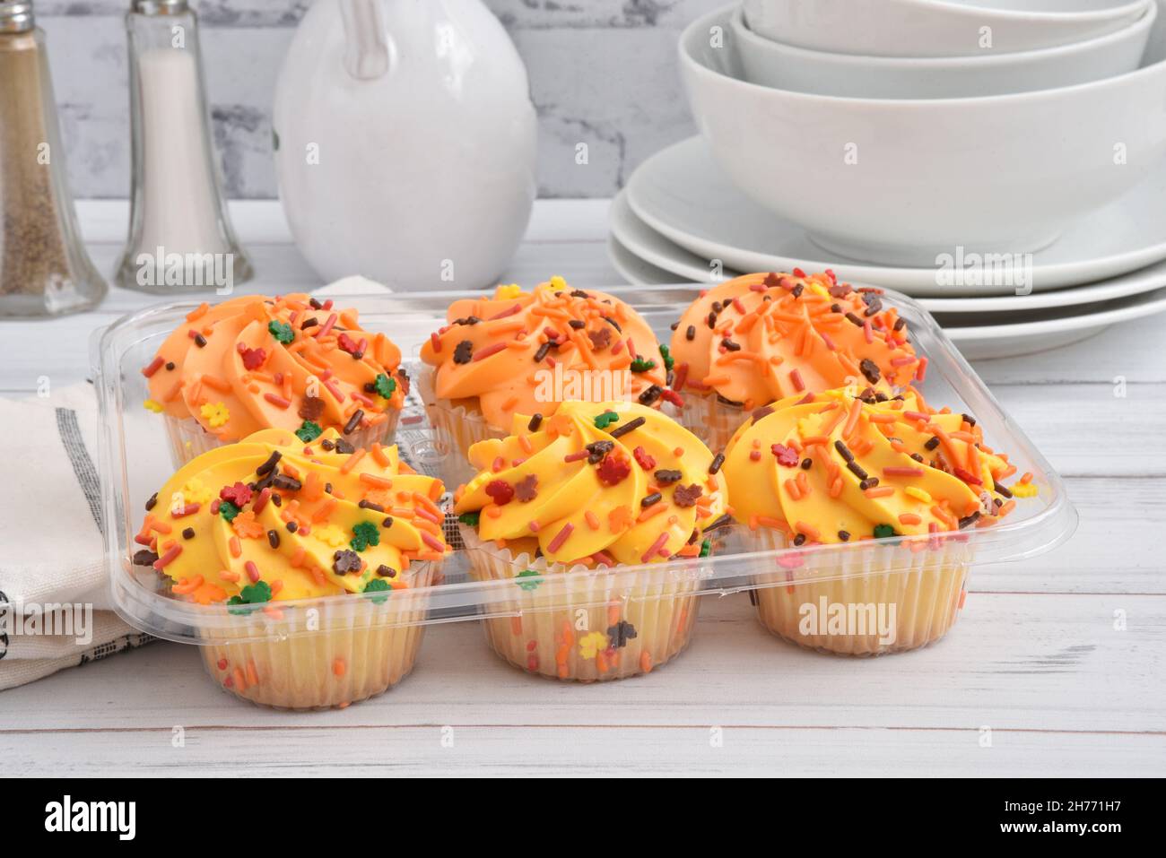 Container of store bought Halloween cupcakes on a rustic white wooden table close up Stock Photo
