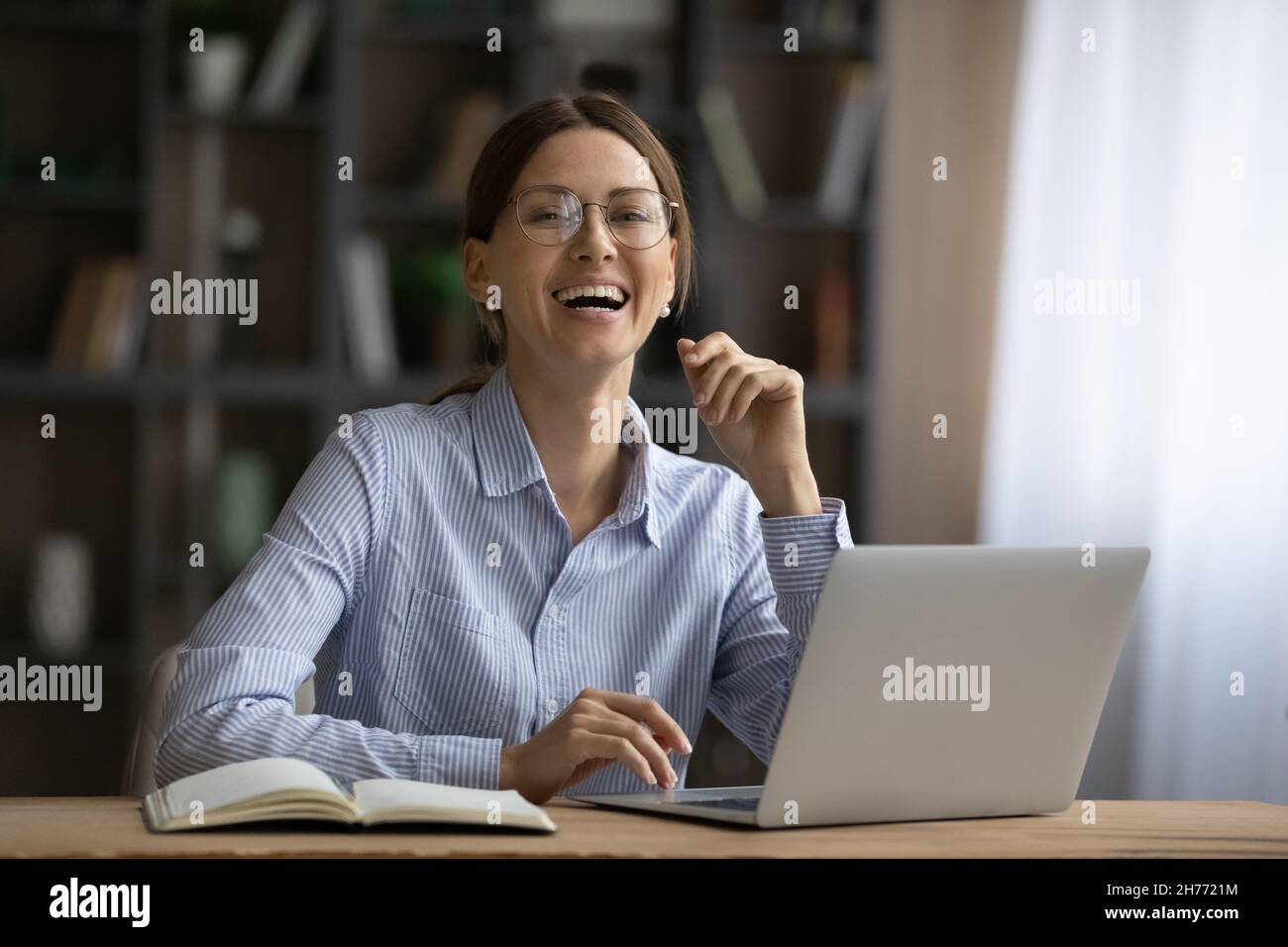 Happy businesswoman sit at desk in front of laptop Stock Photo