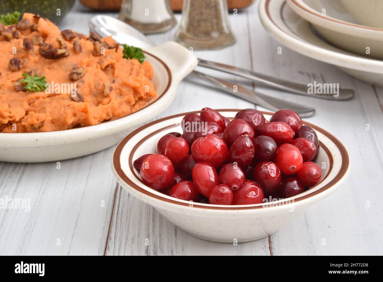 Bowl of fresh cranberries on a holiday dinner table with mashed sweet potatoes Stock Photo