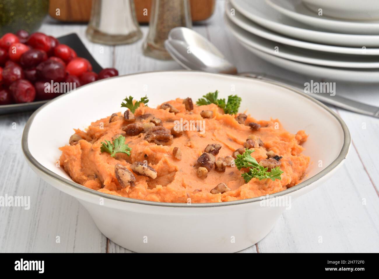 A bowl of homemade mashed potatoes with glazed pecans on a wooden table Stock Photo