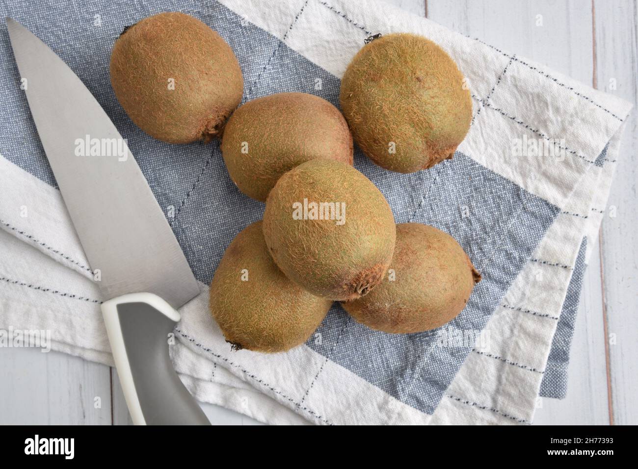 Overhead view of organic kiwi fruit on a towel with a kitchen knife Stock Photo