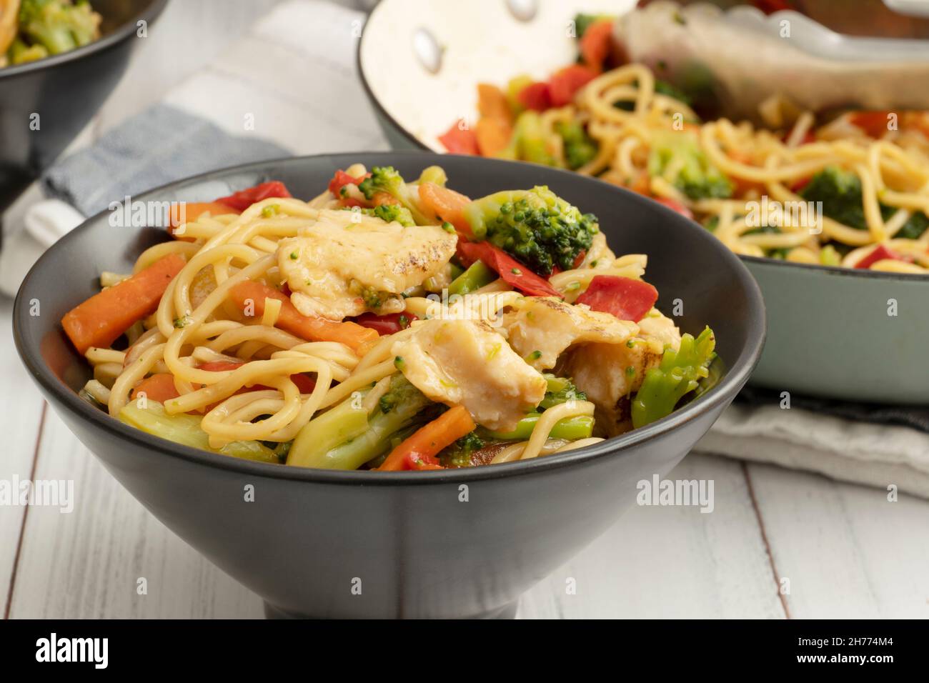A bowl of chicken chow mein with broccoli, carrots, and peppers Stock Photo