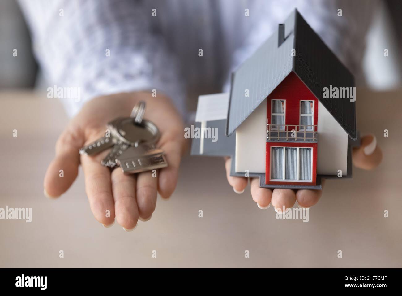 Close up young woman holding keys and house model Stock Photo - Alamy