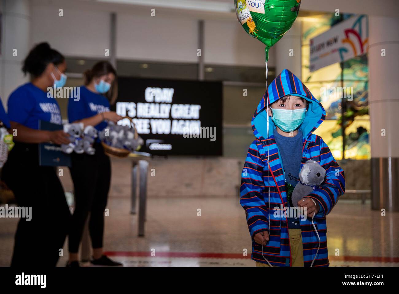 Sydney, Australia. 21st Nov, 2021. People welcome passengers from Singapore at Sydney Airport in Sydney, Australia, on Nov. 21, 2021. Australia's travel bubble with Singapore came into effect on Sunday. Credit: Bai Xuefei/Xinhua/Alamy Live News Stock Photo