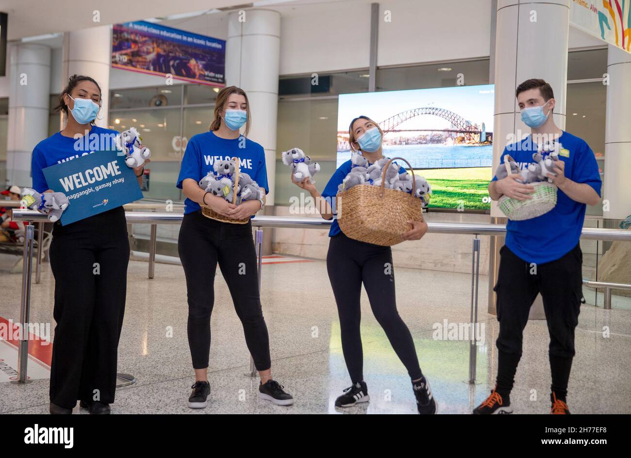 Sydney, Australia. 21st Nov, 2021. People welcome passengers from Singapore at Sydney Airport in Sydney, Australia, on Nov. 21, 2021. Australia's travel bubble with Singapore came into effect on Sunday. Credit: Bai Xuefei/Xinhua/Alamy Live News Stock Photo