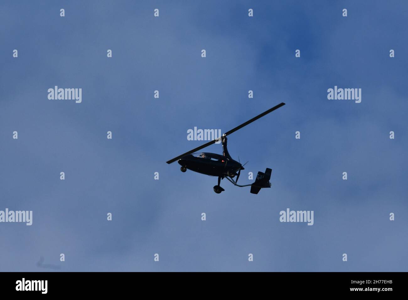 A gyroplane, gyrocopter, autogyro, flying high over rural England on an autumnal day Stock Photo