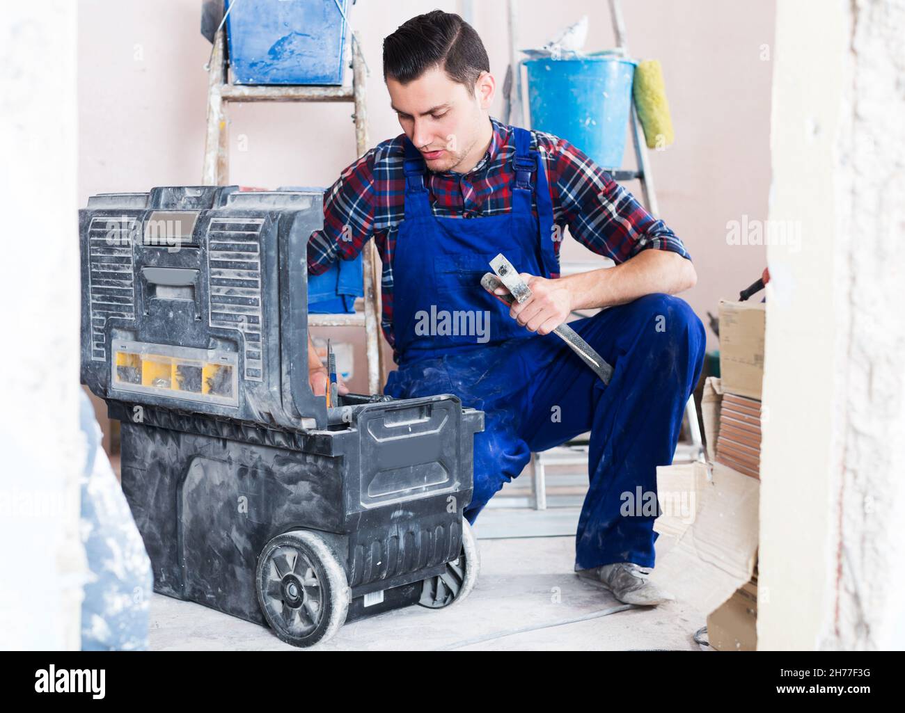 Worker looking for necessary tool in toolbox Stock Photo