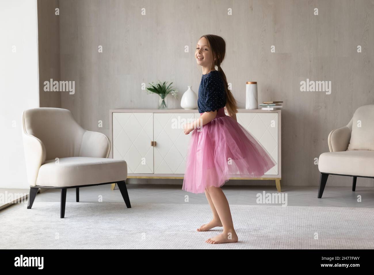 Little girl in pink fluffy skirt standing in living room Stock Photo ...