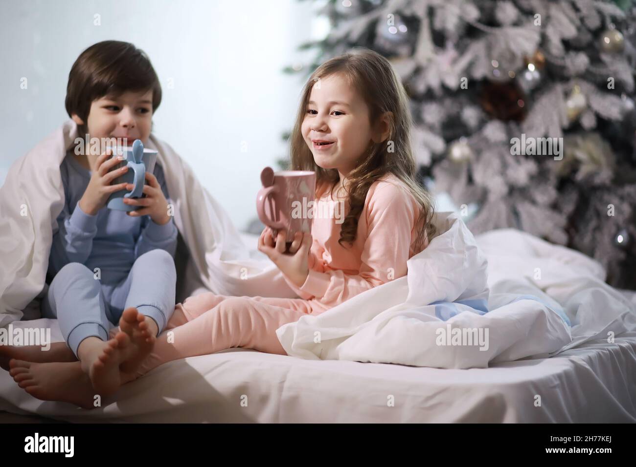 A family with children having fun on the bed under the covers during
