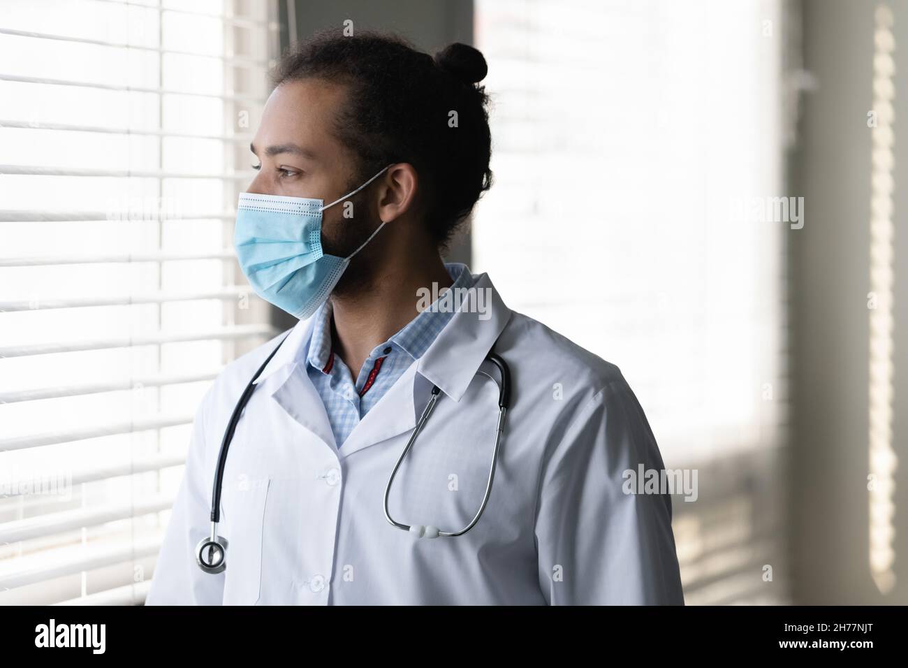 Profile pensive African American man doctor in medical mask thinking Stock Photo
