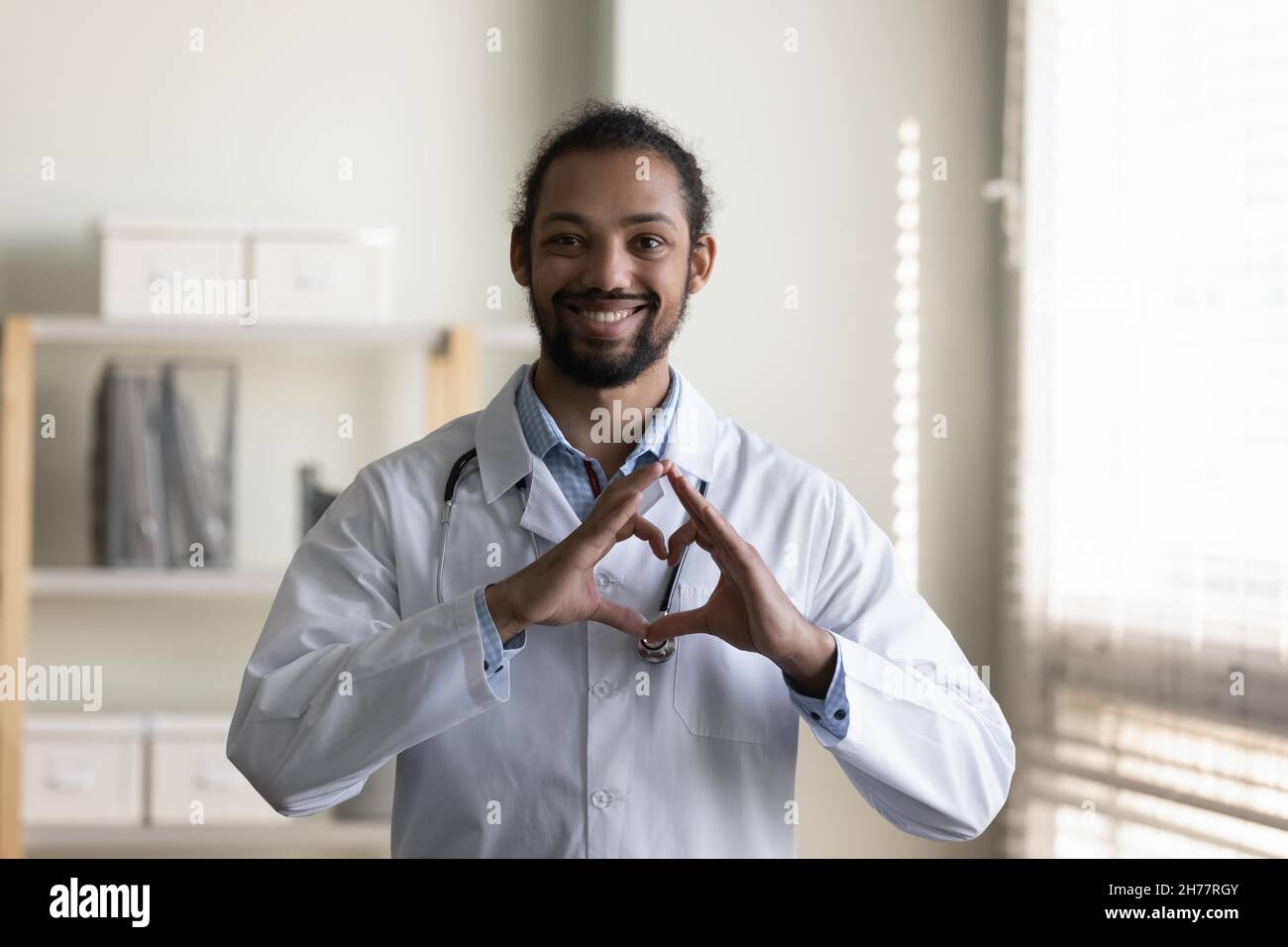 Head shot portrait smiling African American doctor showing heart ...