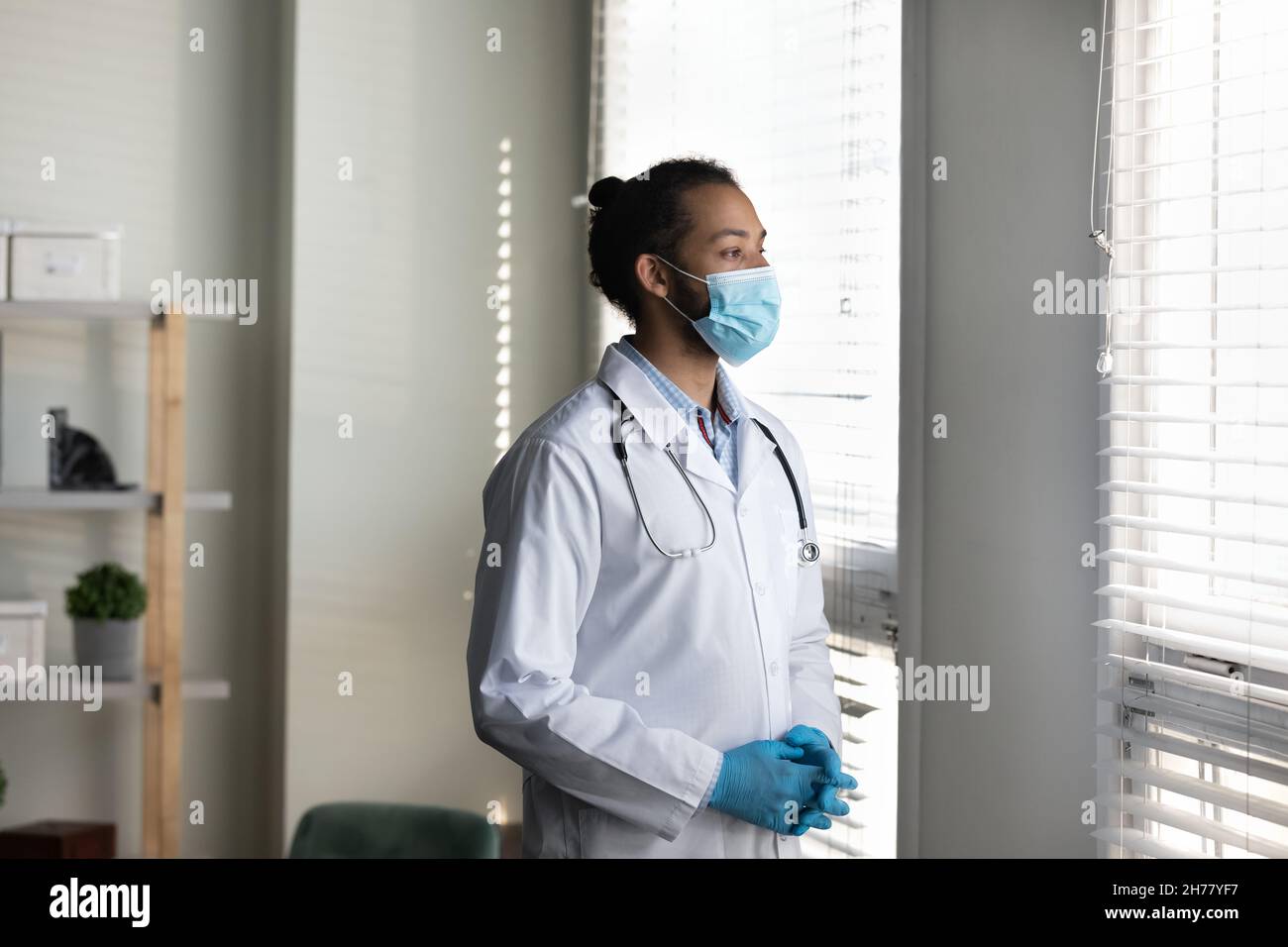 Pensive African American man doctor wearing medical mask thinking Stock Photo