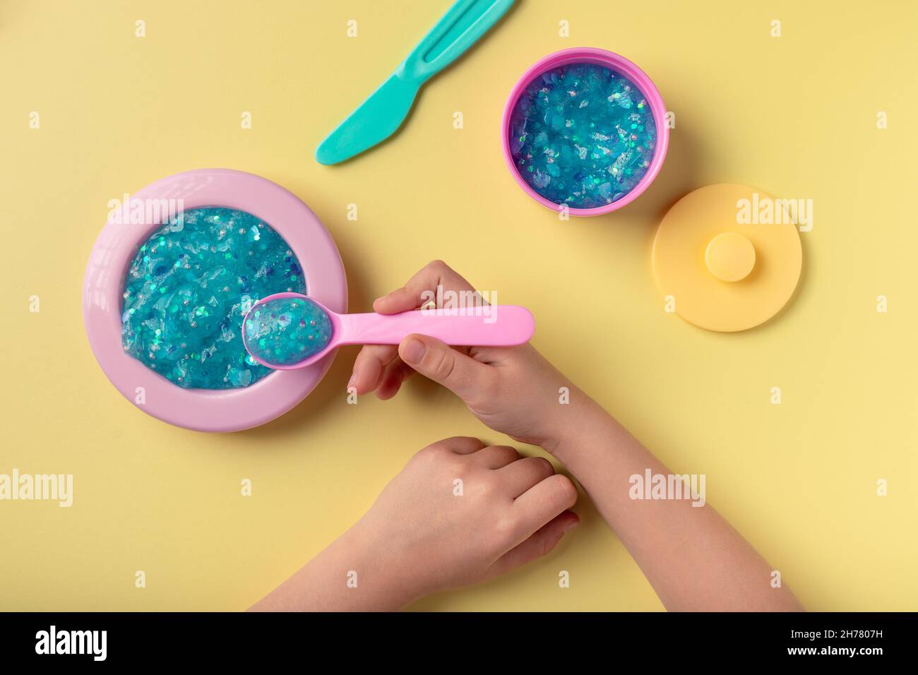 https://c8.alamy.com/comp/2H7807H/girl-playing-with-toy-kitchen-utensils-and-blue-glitter-slime-2H7807H.jpg