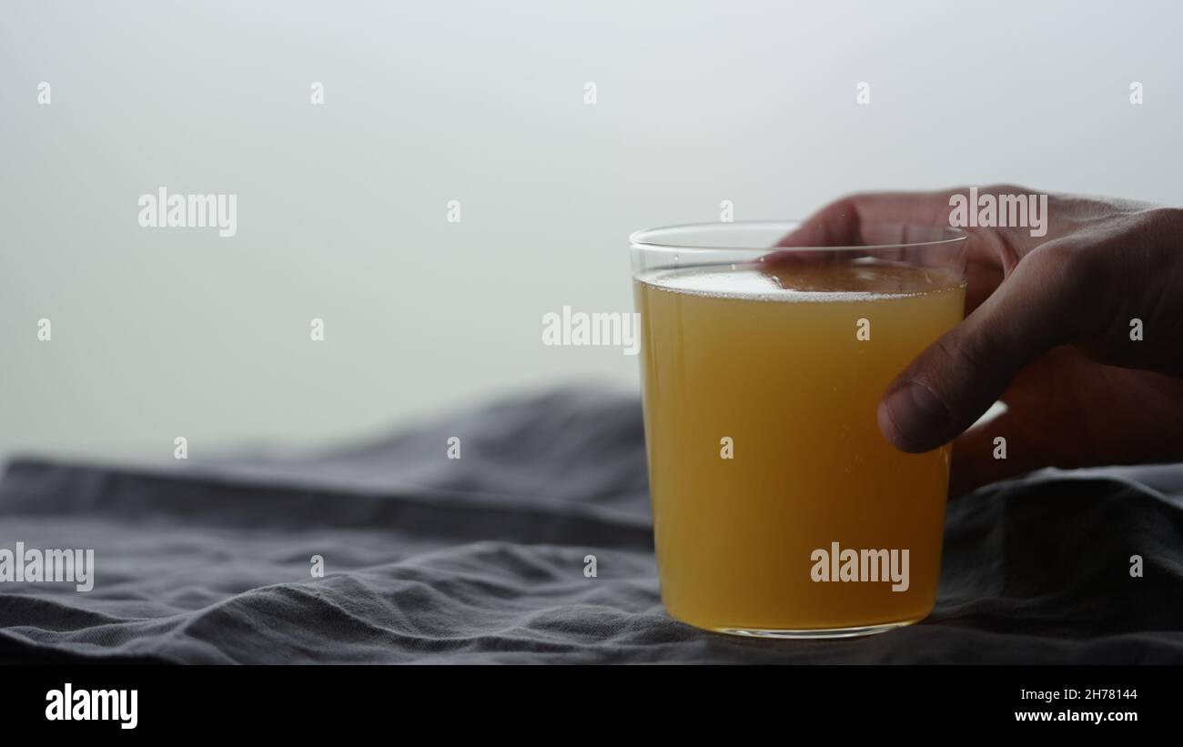 man hand take orange soft drink in tumbler glass from linen cloth, wide photo Stock Photo