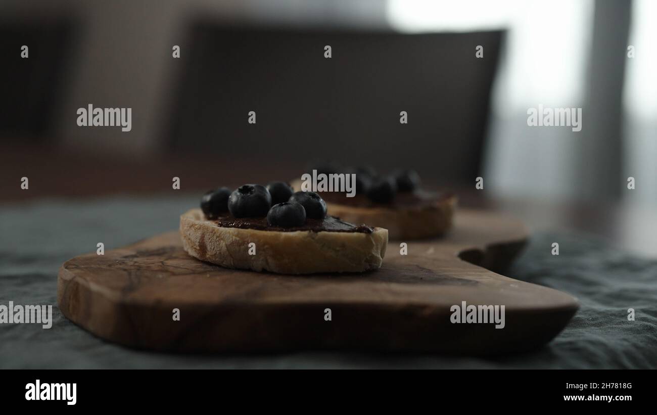 blueberries on chocolate spread on ciabatta slice on dining table, wide photo Stock Photo