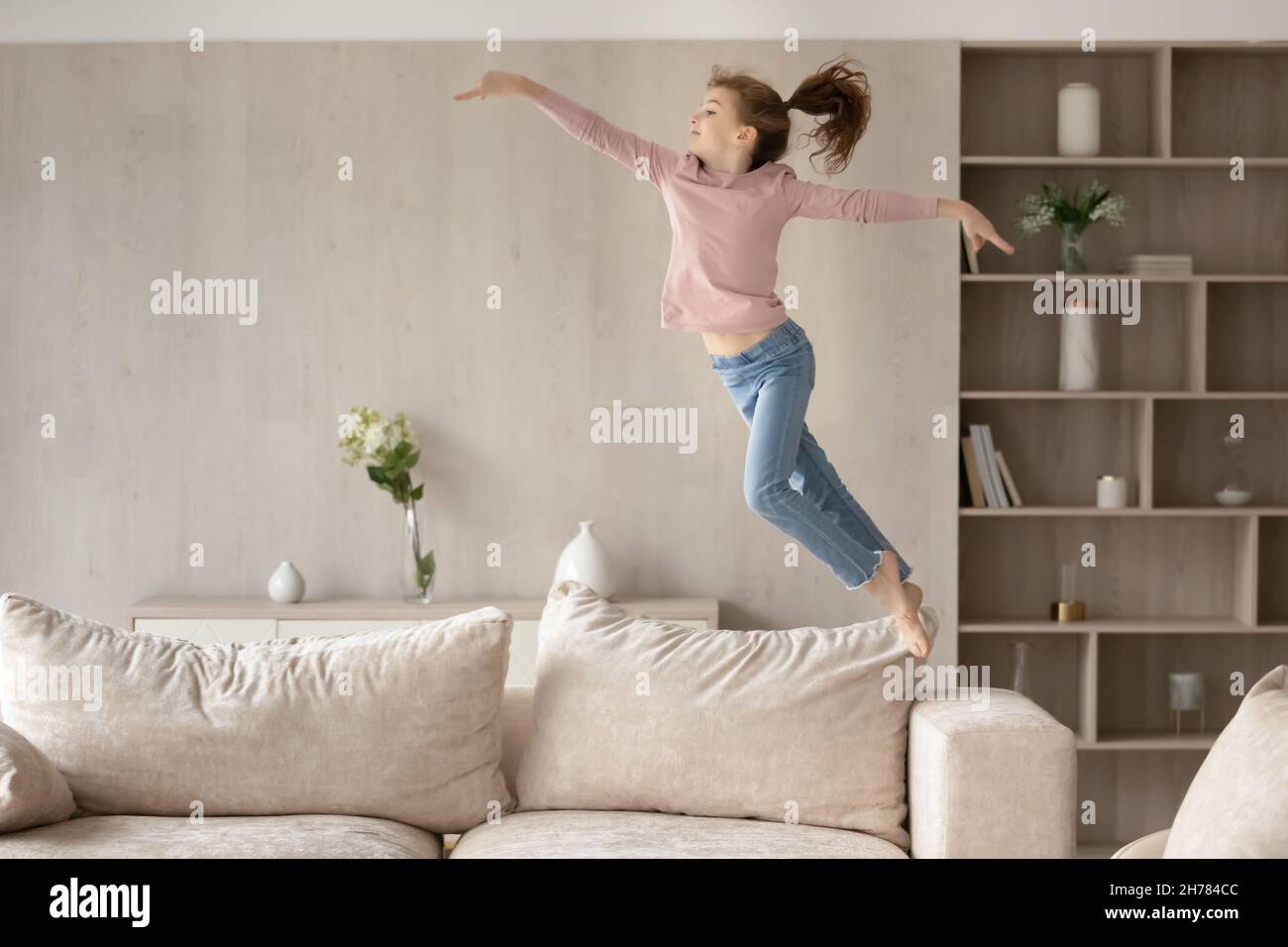 Cute little girl child having fun, jumping high on couch Stock Photo
