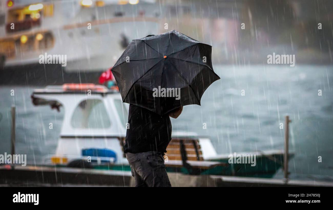 man holding umbrella by the sea on a rainy day Stock Photo