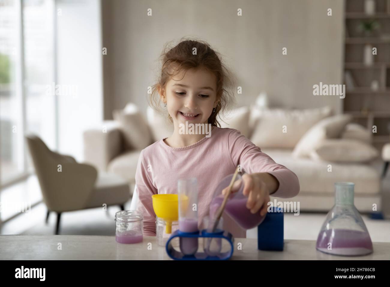 Curious smiling little girl playing with toy laboratory, chemistry experiments Stock Photo
