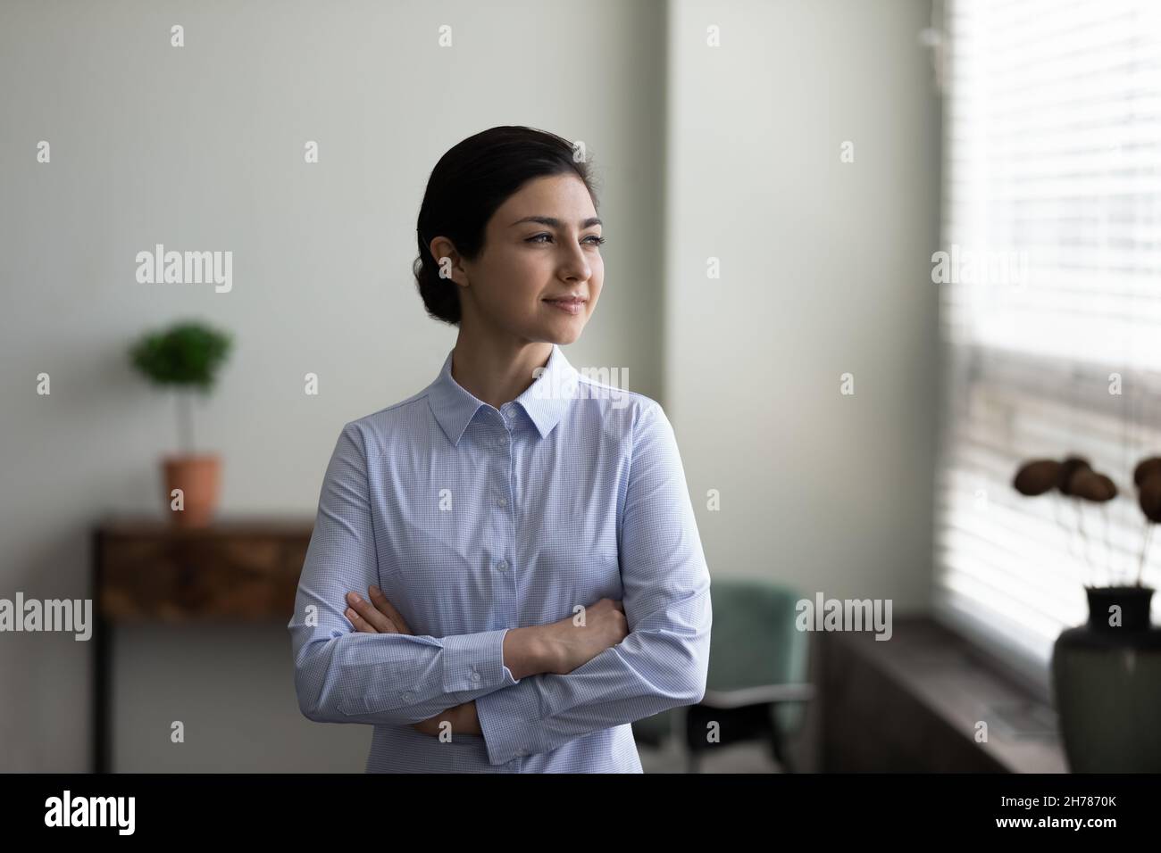 Confident Indian businesswoman with arms crossed looking in distance Stock Photo