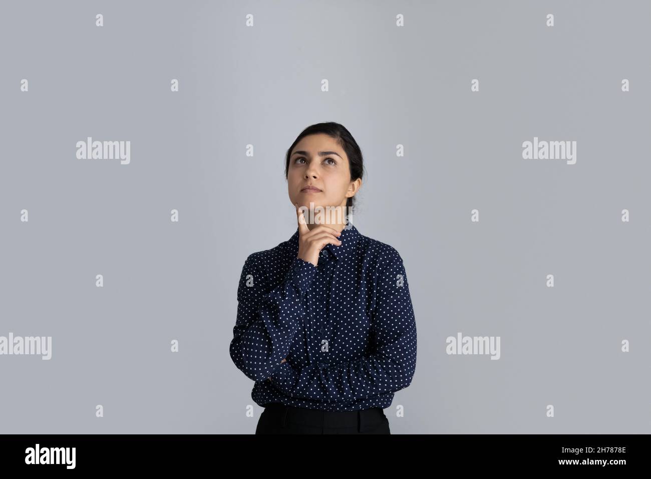 Thoughtful young 30s Indian ethnicity businesswoman considering problem solution. Stock Photo