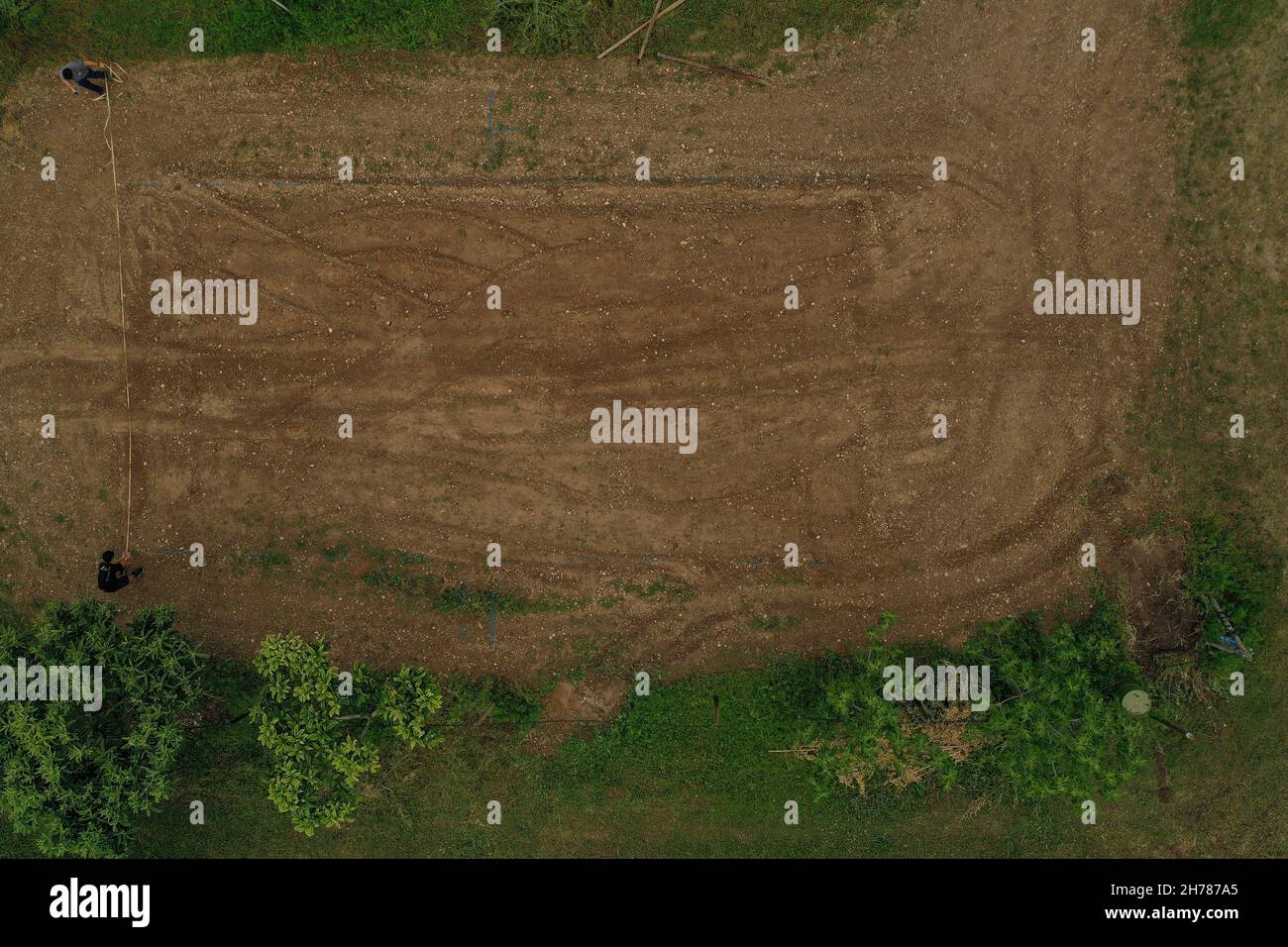 two people measure the width of the uncultivated agricultural field top down view of rural area with  uncultivated field, green and brown with bush an Stock Photo