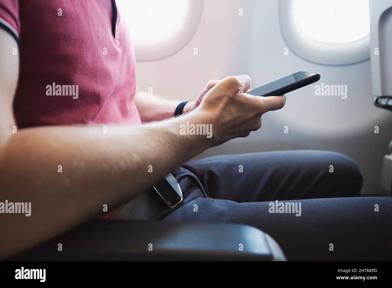 Hands holding smart phone in airplane. Passenger using internet connection during flight. Stock Photo