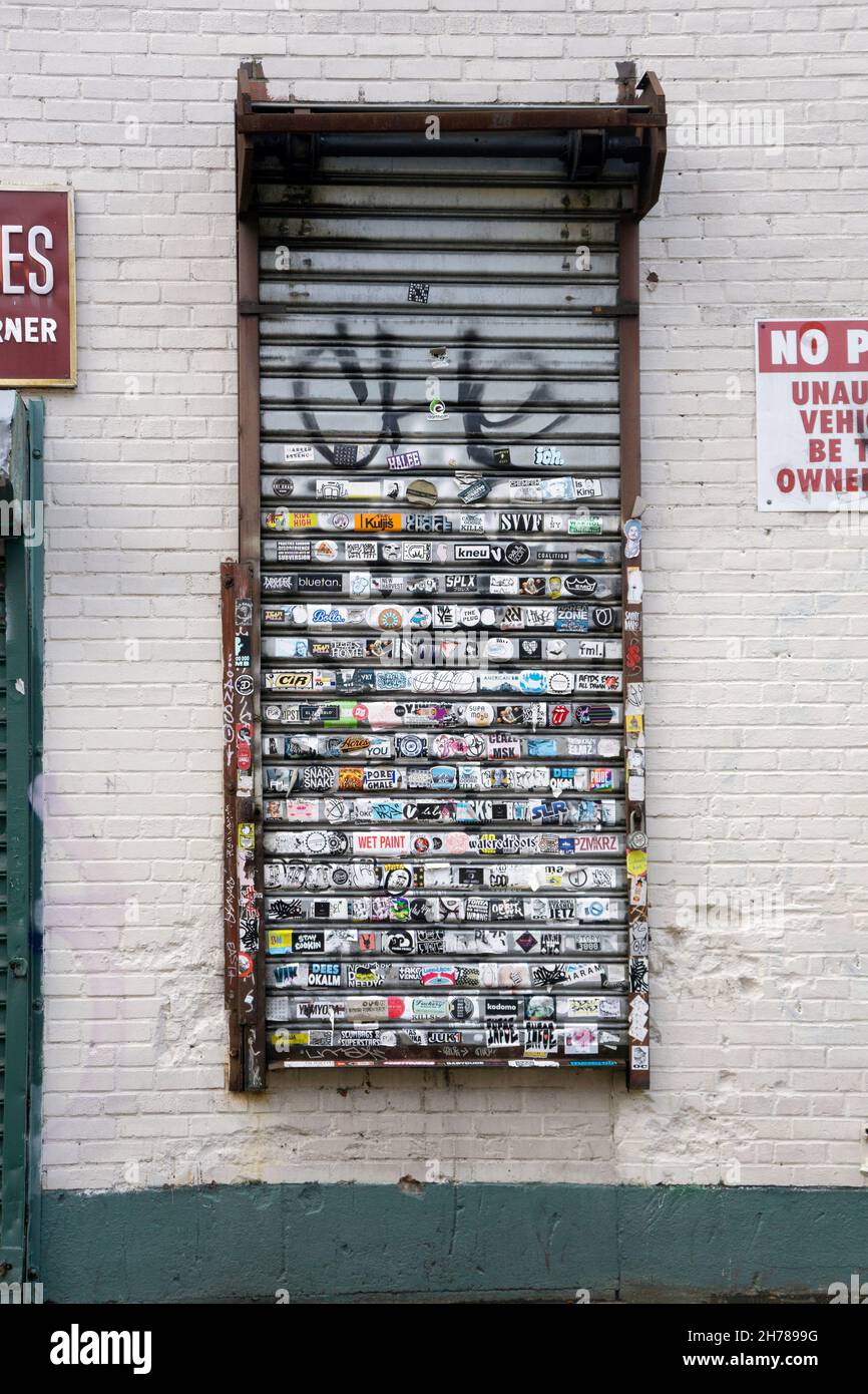 A grating of Grand Street in Williamsburg with lots of stickers and