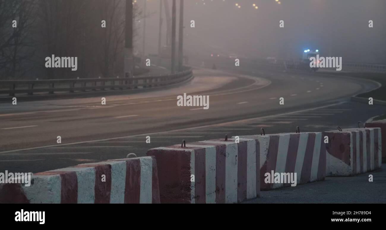 Night, thick fog over highway. Part of road is lockdown with concrete blocks Stock Photo