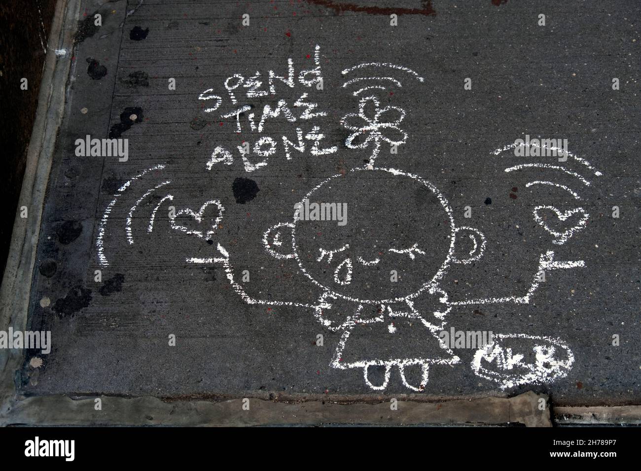 A chalk drawing on a sidewalk in Greenwich Village suggesting we spend time alone. In New York City. Stock Photo