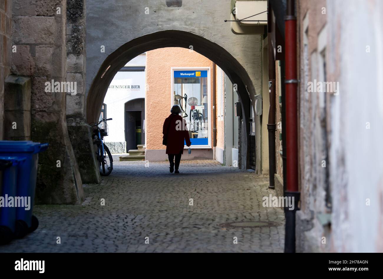Bad Reichenhall, Germany. 21st Nov, 2021. A woman walks through the old  town with a mouth guard in her hand. Currently, nine Bavarian counties have  an incidence of over 1000. Credit: Sven