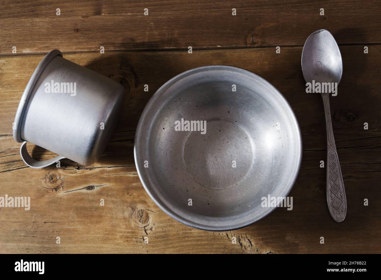 Empty aluminum dish, spoon and overturned mug on the old wooden table Stock Photo