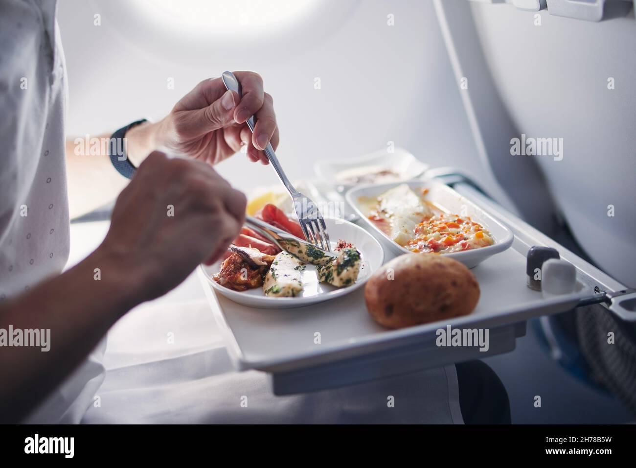 Passenger eating airline meal in airplane. Menu in business class on medium haul flight. Stock Photo